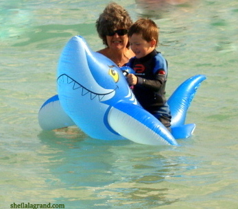child in ocean on inflatable shark